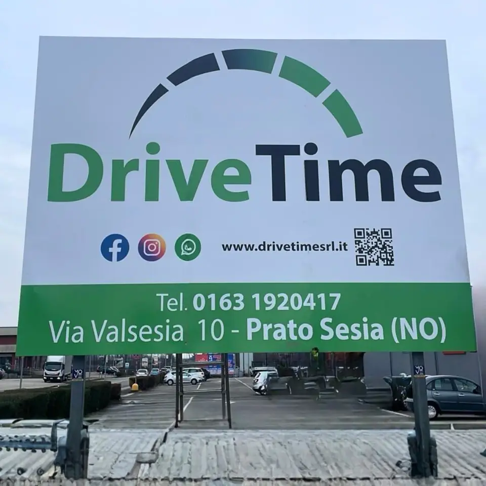 Cartello pubblicitario DriveTime su due pali, con logo verde, sito, QR code e contatti