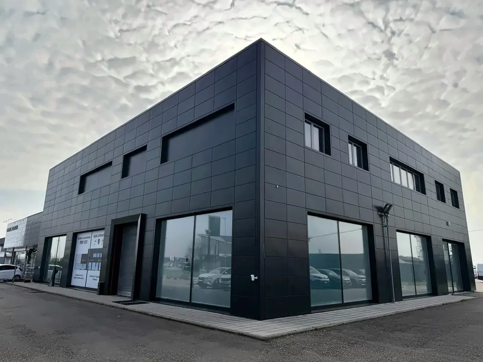 Edificio a cubo con rivestimento scuro in facciata e vetrate a nastro