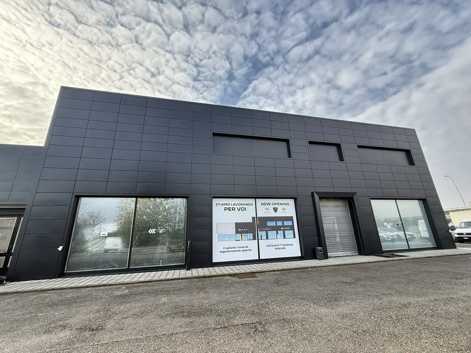 Edificio commerciale con facciata rivestita in pannelli scuri e vetrine al piano terra