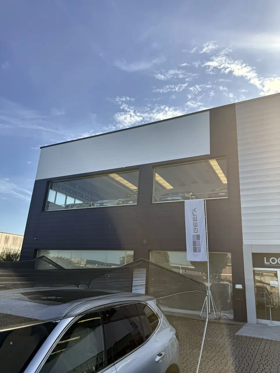 Facciata moderna con rivestimento a pannelli scuri e grandi vetrate, vista dal basso