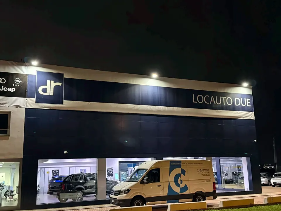 Facciata illuminata di notte con insegna e un furgone parcheggiato davanti