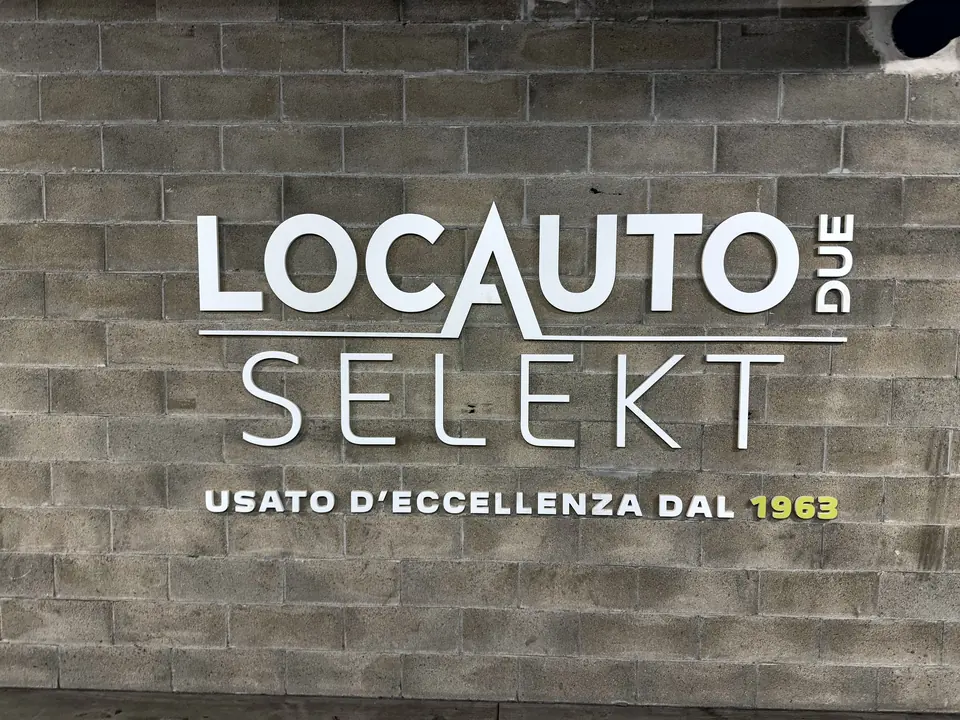 Insegna a lettere in acciaio montata su una parete in mattoni