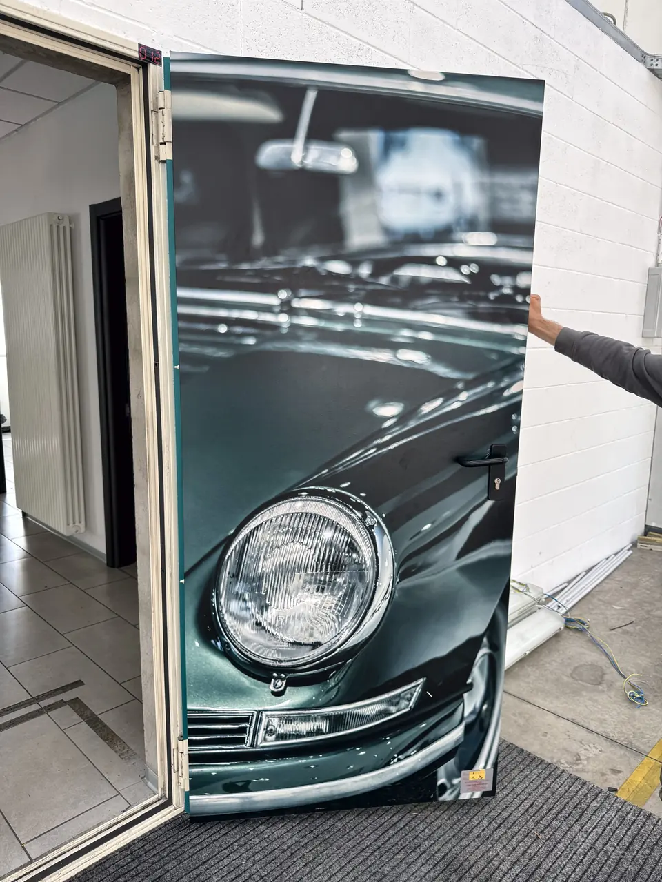 Pannello fotografico con un'auto d'epoca in primo piano, in uno showroom