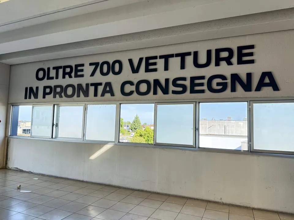 Scritta in lettere tridimensionali sulla parete di uno showroom auto, sopra le vetrate
