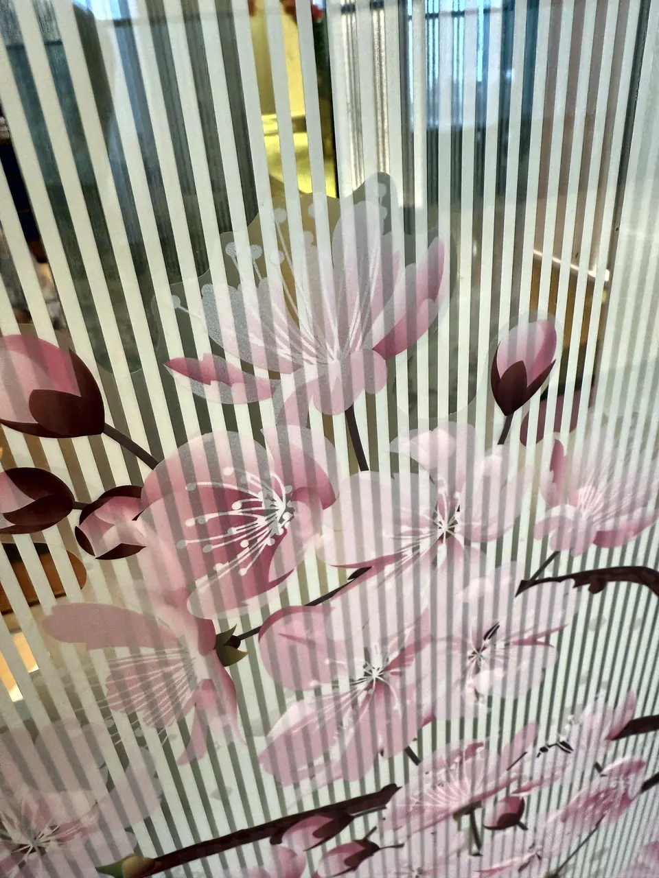 Dettaglio di una vetrofania con fiori di ciliegio e righe satinate